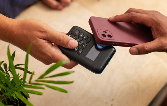 Diverse vendor, customer paying at counter: vendor pressing POS key while customer tapping phone