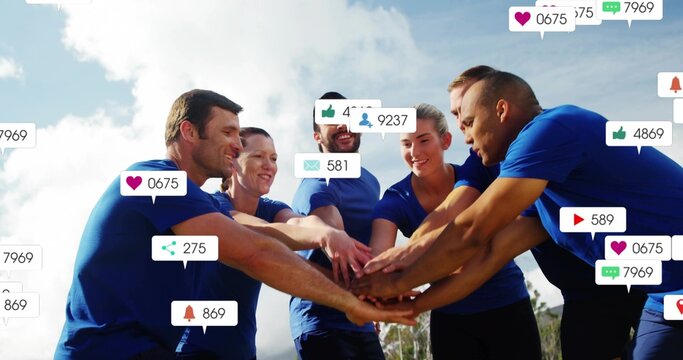Huddling six adults in blue athletic shirts stacking hands in park, showing social-media overlays