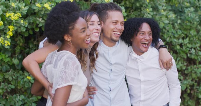 Diverse friends laughing, leaning in, hugging each other before flowering hedge after prompt