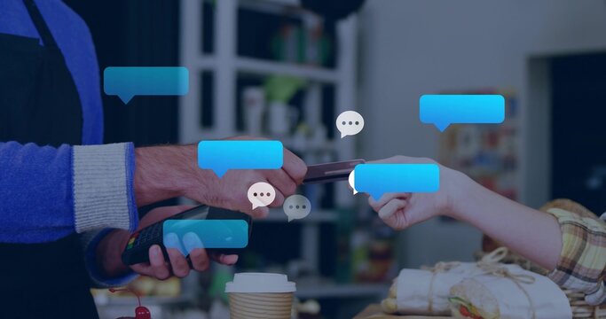 Exchanging phone and terminal, barista in apron and customer in plaid shirt paying at cafe counter