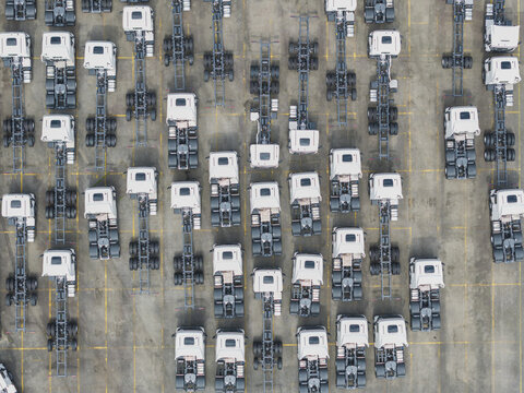 Aerial view of numerous white semi-truck chassis parked in organized rows at a truck dealership in Taiwan.