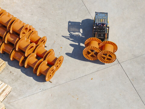 Aerial view of a forklift operator moving large orange cable reels in the outdoor yard of a cable factory in Taiwan.