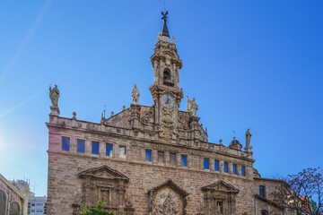 Fototapeta premium Ciutat Vella,Valencia,Spain,Historic stone church with ornate facade and bell tower under clear blue sky