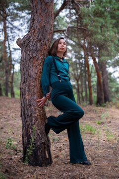 Woman Leaning Against Tree in Pine Forest