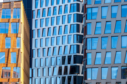 Modern urban corporate offices and buildings facade with glass windows and tilted architecture pattern creating dynamic diagonal geometry in city exterior