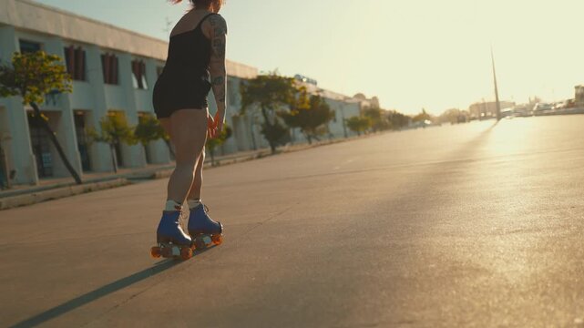 Tattooed woman rollerskating during golden hour sunset