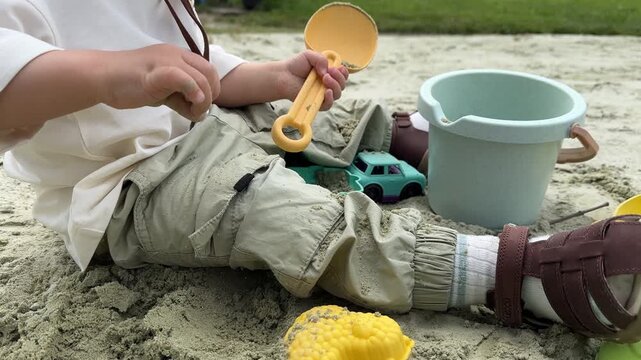 Toddler playing in sandbox with toy shovel and bucket