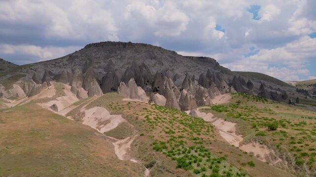 Panoramic Drone View of Selime Fairy Chimneys Hillside, A wide aerial vista capturing the cluster of cone-shaped rock pillars and ancient caves scattered across the hillside.