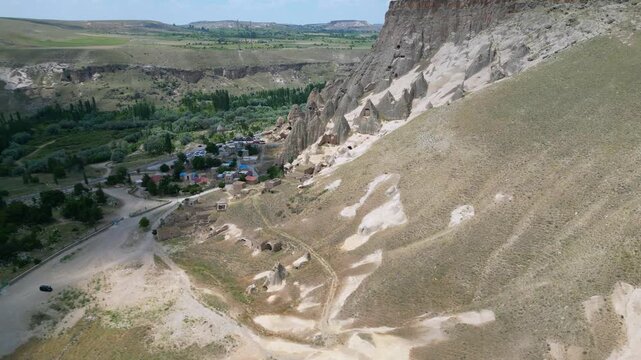 Aerial Perspective of Selime Village and Ancient Rock Monastery. A wide-angle drone view showing the historic Selime Monastery perched above the modern Turkish village.