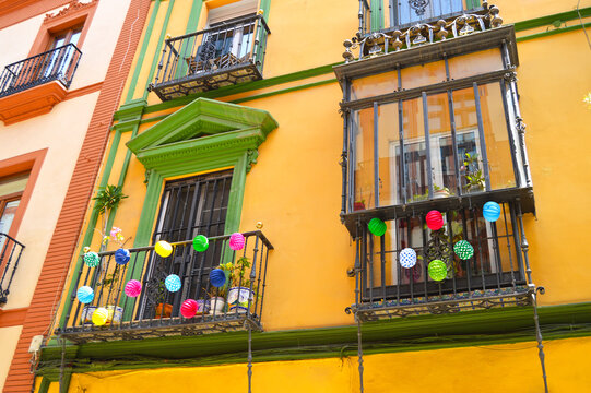 Balconies of a typical house in Seville decorated with multicolored paper lanterns for the April Fair (Feria de Abril). Seville Fair (Feria de Sevilla). Cheerful, joyful, colorful and fiesta.
