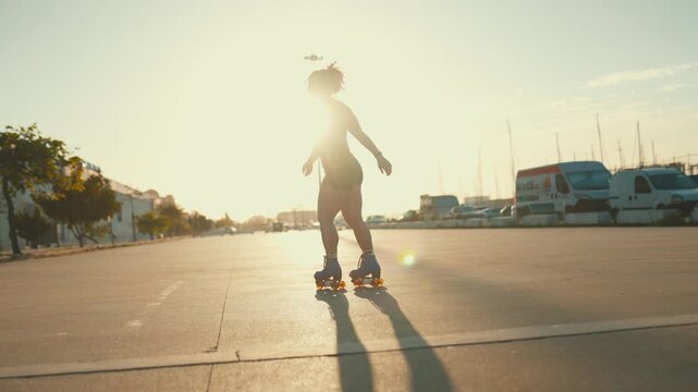 Young woman dancing on roller skates at sunset