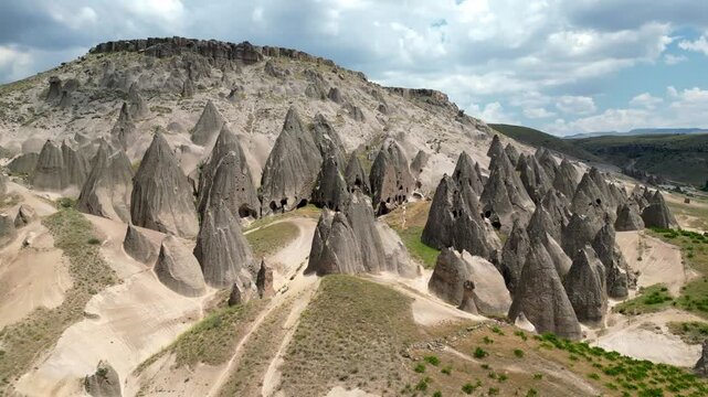 Cinematic Drone Flyover of Rock Ridges in Selime Cappadocia, A smooth aerial tracking shot flying along the dramatic volcanic rock ridges and cone-shaped pillars of the Selime fairy chimney valley.