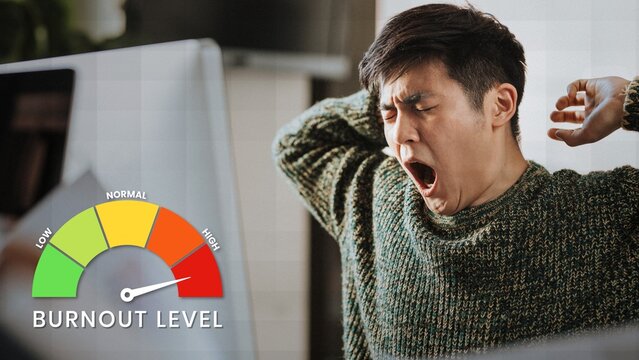 Man yawning at desk with burnout level gauge showing high stress