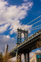 Naklejka premium Stunning view of Manhattan Bridge with clouds drifting above on a sunny day