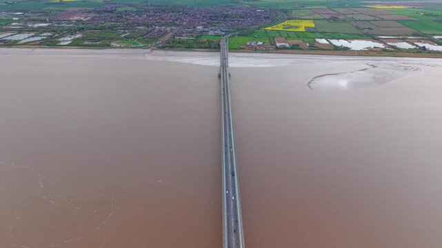 Aerial perspective of commuter traffic crossing the Humber Bridge above the wide brown silt waters of the estuary