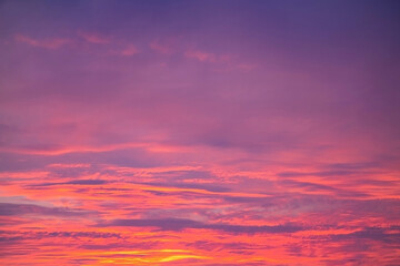 Obraz premium Vibrant layers of purple, pink and orange clouds fill the sky in a stunning sunset scene