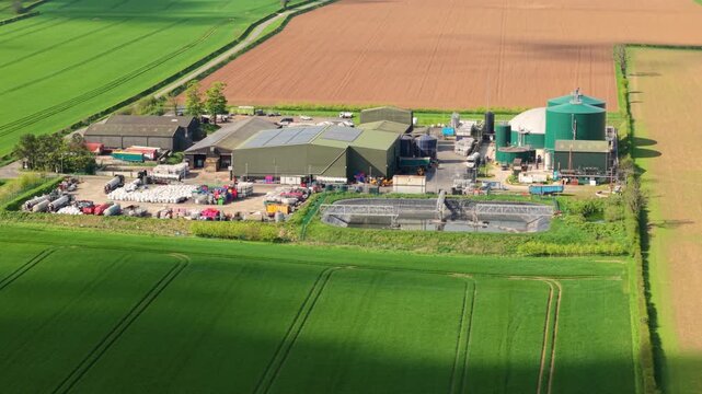 Aerial drone view of a biogas renewable energy facility with anaerobic digesters in rural Lincolnshire fields UK