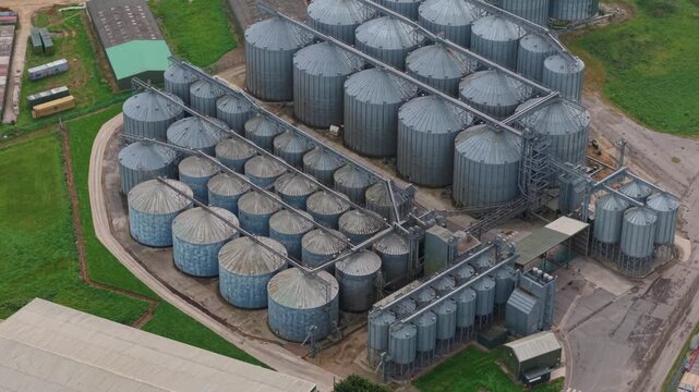 Aerial top down view of galvanized steel grain storage silos on a rural farm in the UK, agricultural infrastructure for cereal crop harvesting.