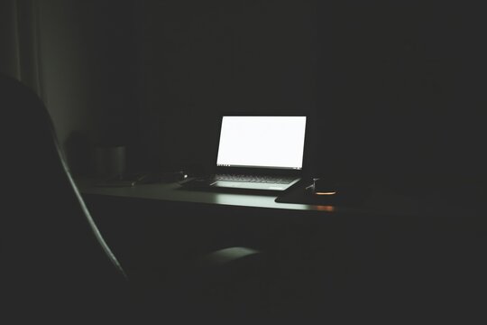 Dark workspace with laptop glow in moody light