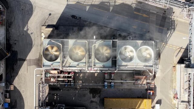 Close up aerial view of industrial turbine fans and vents rotating with steam rising in the UK