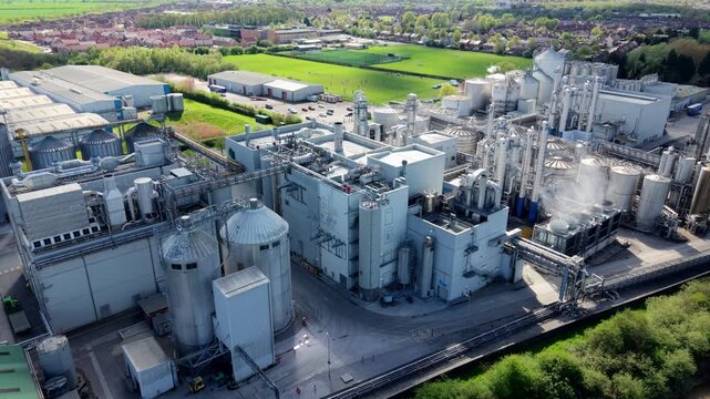Aerial view of a massive industrial factory with manufacturing infrastructure and storage silos on the banks of the River Aire in Yorkshire