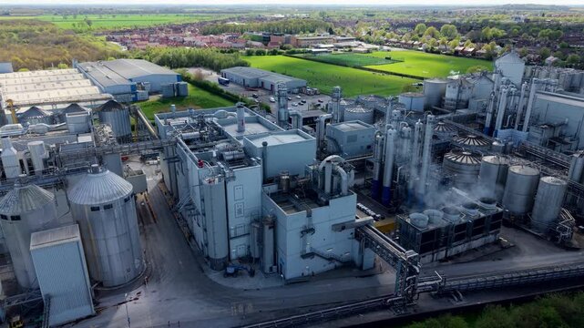Aerial view of a massive industrial factory with manufacturing infrastructure and storage silos on the banks of the River Aire in Yorkshire