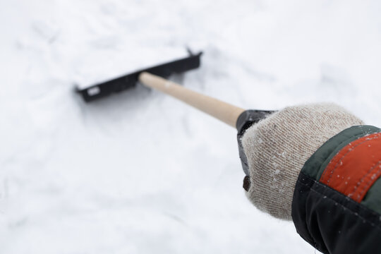 a hand in a knitted glove in perspective, clutching a shovel