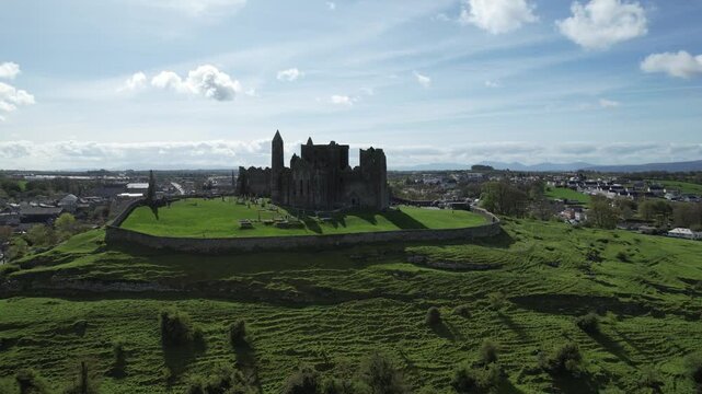 Aerial drone view of the Rock of Cashel, a historic medieval cathedral and fortress rising above the Irish countryside.