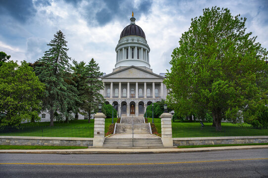 Maine State Capitol in Augusta, featuring neoclassical architecture, central dome, and landscaped grounds under a cloudy sky