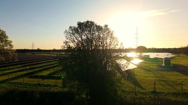 Low aerial flight over Tiln solar farm at sunset with golden light reflecting off photovoltaic panels UK