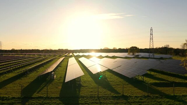Low aerial flight over Tiln solar farm at sunset with golden light reflecting off photovoltaic panels UK