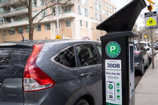 Close up of municipal parking meter with parked car on city street. Toronto, Canada - April 19, 2026.