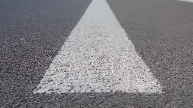 A textured black asphalt road with a white painted stripe in the center