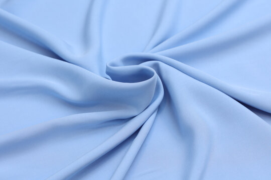 Premium blue 100% natural viscose fabric texture with elegant, soft drapes. Lightweight, breathable textile background in vibrant colors. Ideal for fashion design, apparel manufacturing, and sewing.