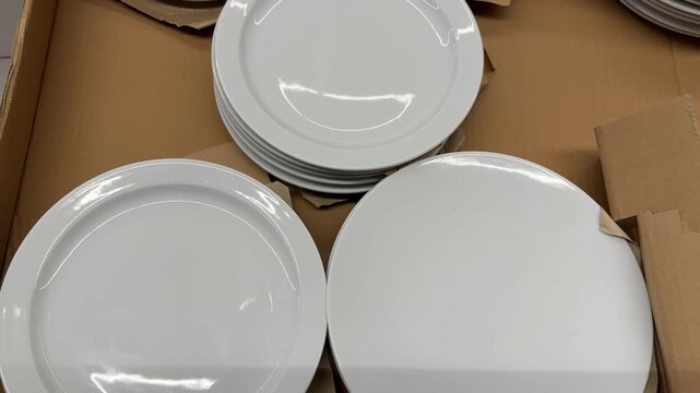 White ceramic dinner plates arranged in cardboard box for kitchenware background