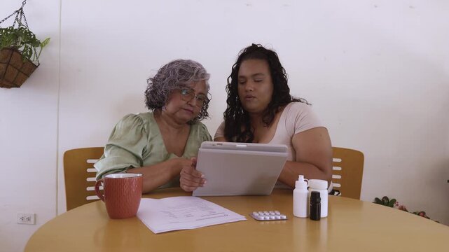 Caregiver assisting senior woman with online medical information