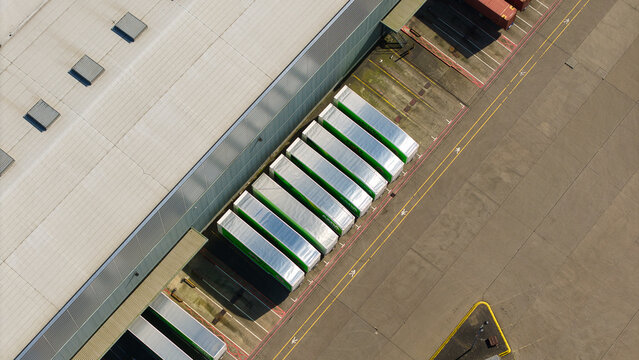 Aerial view of Magna Park featuring a large warehouse roof and a row of semi-trailers parked at loading docks in Magna Park, England, United Kingdom.