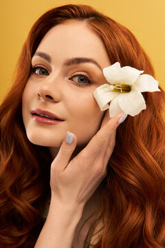 Elegant young woman with red hair and flower enjoys a moment of beauty and fashion