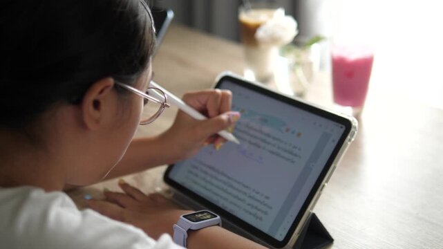 Extreme close-up of a young girl's hand with cute colorful nail art using a white digital stylus to write or draw on a tablet screen, modern e-learning concept