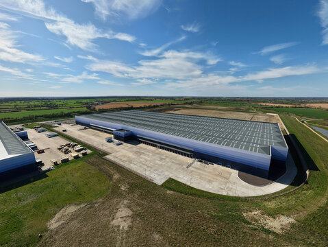 Aerial view of large modern warehouse facility with blue facade and surrounding green fields Magna Park, England, United Kingdom.