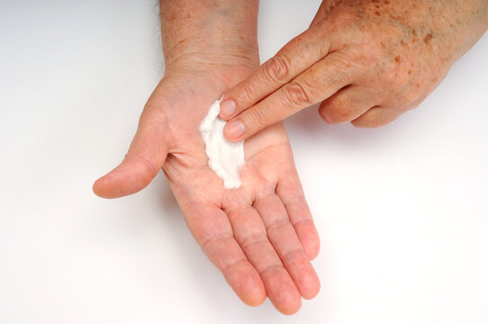 Applying skincare cream to the palm of a woman&rsquo;s hand