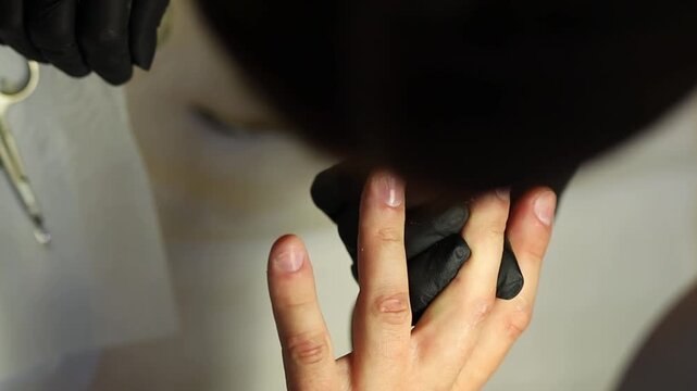 Men's manicure. Male hand undergoing a manicure procedure. The master does a man's manicure. A manicurist files a man's nails in a salon. Hygiene and hand care for men. Men's manicure design.