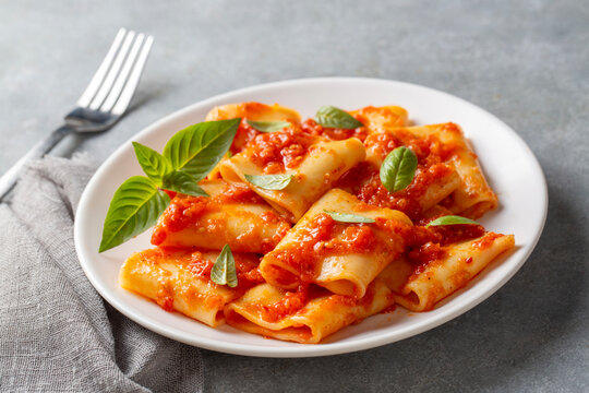 Paccheri allo Scarpariello Pasta with Tomato Sauce and Fresh Basil on a White Plate