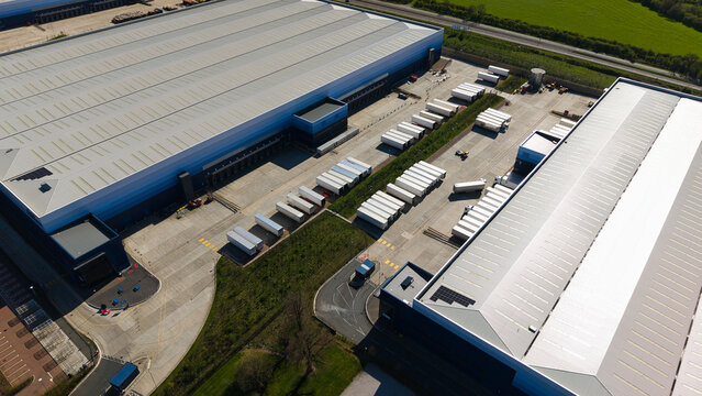 Aerial view of large industrial warehouses and rows of white semi-trailers at loading docks in Magna Park, England, United Kingdom.