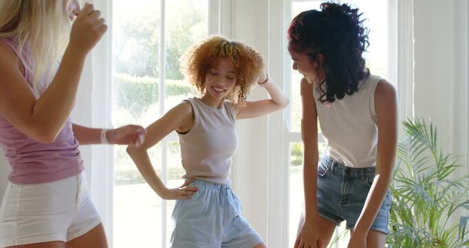 Dancing three women swaying and punching at home by glass doors, wearing summer clothes, wristwatch