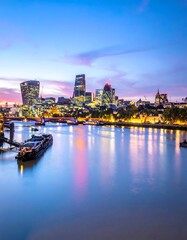 Obraz premium City skyline at dusk over a wide river with a boat
