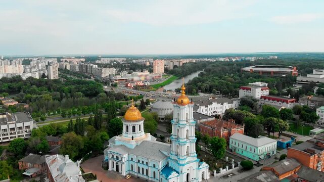 Wide aerial drone view of Sumy city center in Ukraine featuring the Transfiguration Cathedral with golden domes surrounded by historic buildings and green urban spaces