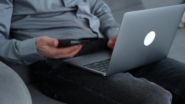 Remote worker in a home environment sitting on a couch with a laptop, engaged in online client communication and text input work