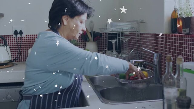Senior woman lifting bowl and washing veg prepping at kitchen sink with star overlay showing water