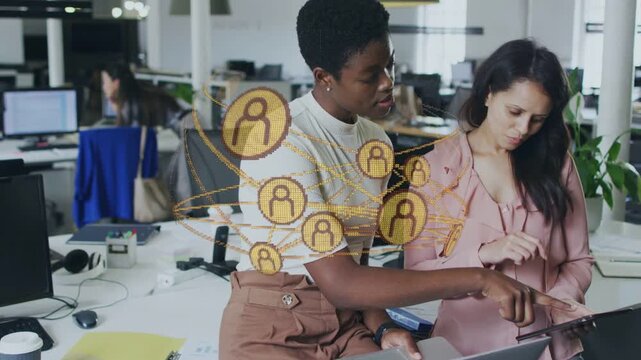 Lead pointing at laptop, causing golden icons orbiting as peer tapping tablet, working business